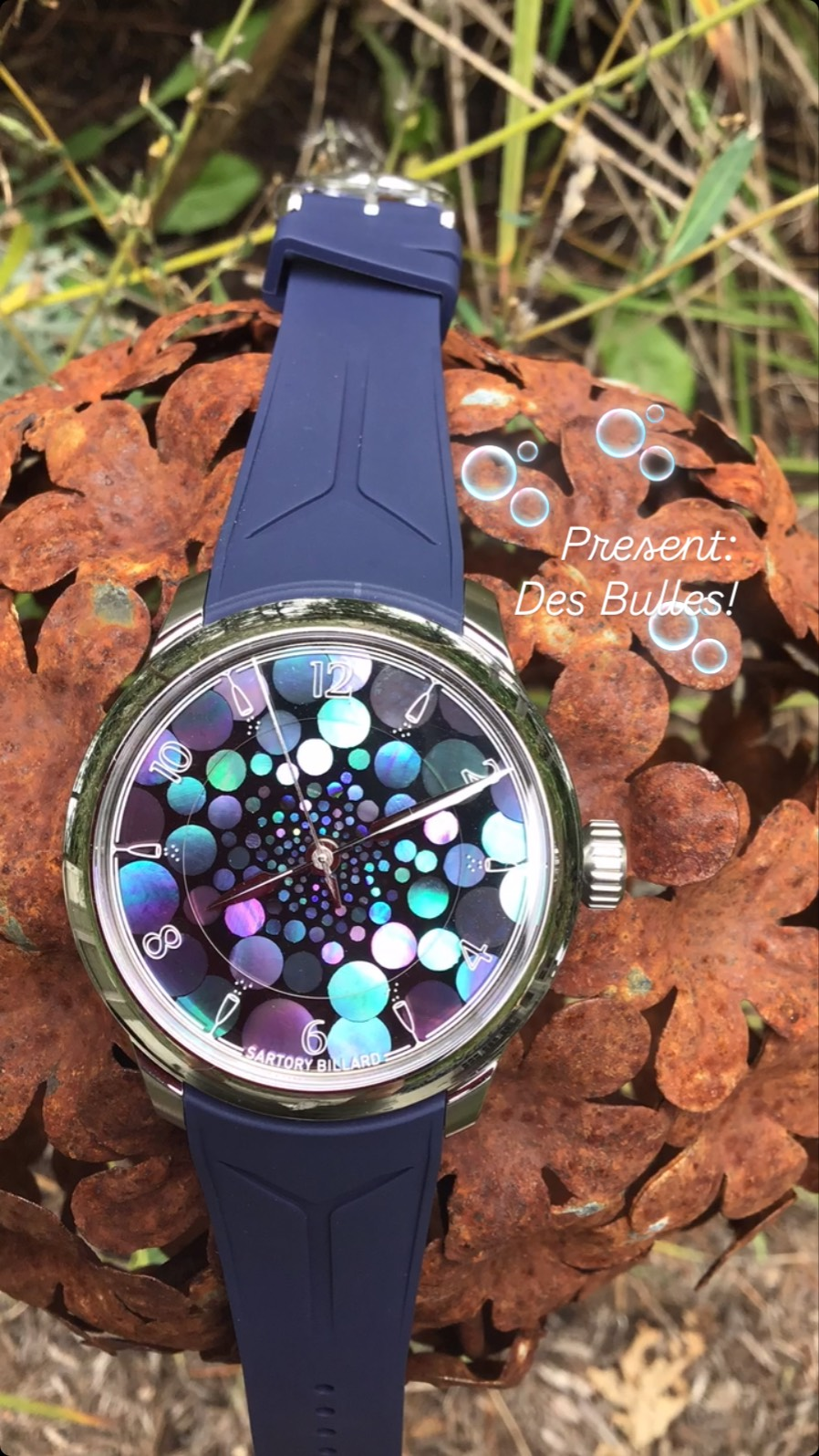 @sartorybillard 🇫🇷 in collaboration with @martinpulli 🇺🇸
A French Ritual, Reimagined in Japanese Lacquer
Created in collaboration with American collector and retailer Martin Pulli, the SB04-E 
Des Bulles is a limited edition of 26 pieces inspired by a glass of champagne seen directly from
above.
The project takes its name from the familiar French invitation “des bulles?”
, or “some bubbles?”,often heard at the beginning of the apéro. Armand Billard translated this simple
expression of conviviality into a dial where circles of mother-of-pearl appear to rise through
black lacquer, evoking the bubbles, reflections and movement inside the glass.
Each dial is individually composed by Japanese lacquer artist Tatsuya Todo using the
traditional art of raden. Champagne-glass markers, outlined numerals and newly developed
spear-shaped hands complete a playful interpretation shaped through an ongoing creative
dialogue with Martin Pulli.
A Glass Seen From Above:
Rather than drawing on the familiar imagery of champagne bottles and labels, Armand
approached the subject through the experience of looking directly into the glass.
Circles of mother-of-pearl become progressively smaller towards the centre of the dial,
creating a sense of perspective and depth. Their natural iridescence reveals changing
reflections of turquoise, violet, green, blue and pink, bringing movement to the composition
as the watch catches the light.
A double white line suggests the rim of the glass, while stylised champagne flutes replace
the conventional markers at the odd hours. Outlined numerals inspired by the expressive
typography of champagne labels reinforce the identity of the watch without turning the dial into a literal interpretation.